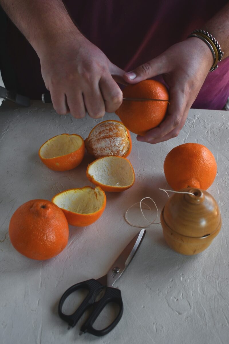 Gently slicing an orange to remove the peel only.