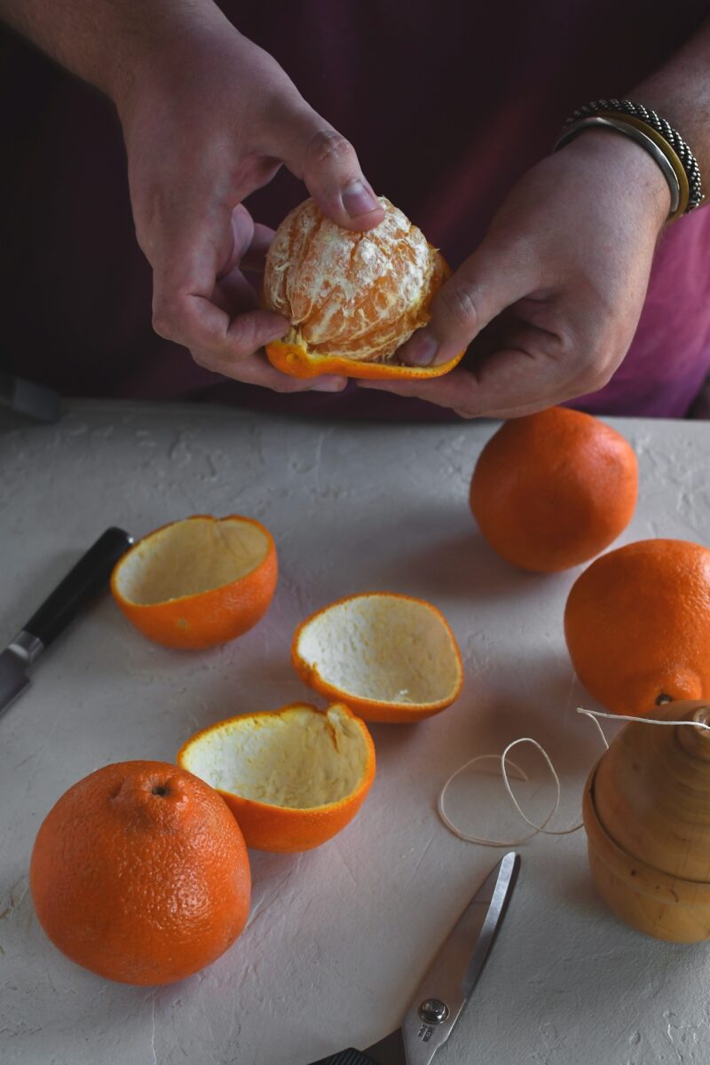 Gently removing the peel from an orange, keeping it intact in one large piece.