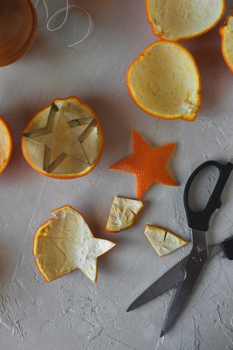 Using a star cookie cutter to score the orange peel, then using scissors to cut them out.