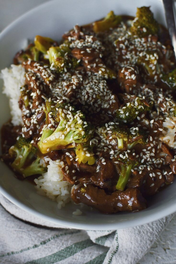 Looking into a bowl of Slow Cooker Beef and Broccoli topped with sesame seeds.
