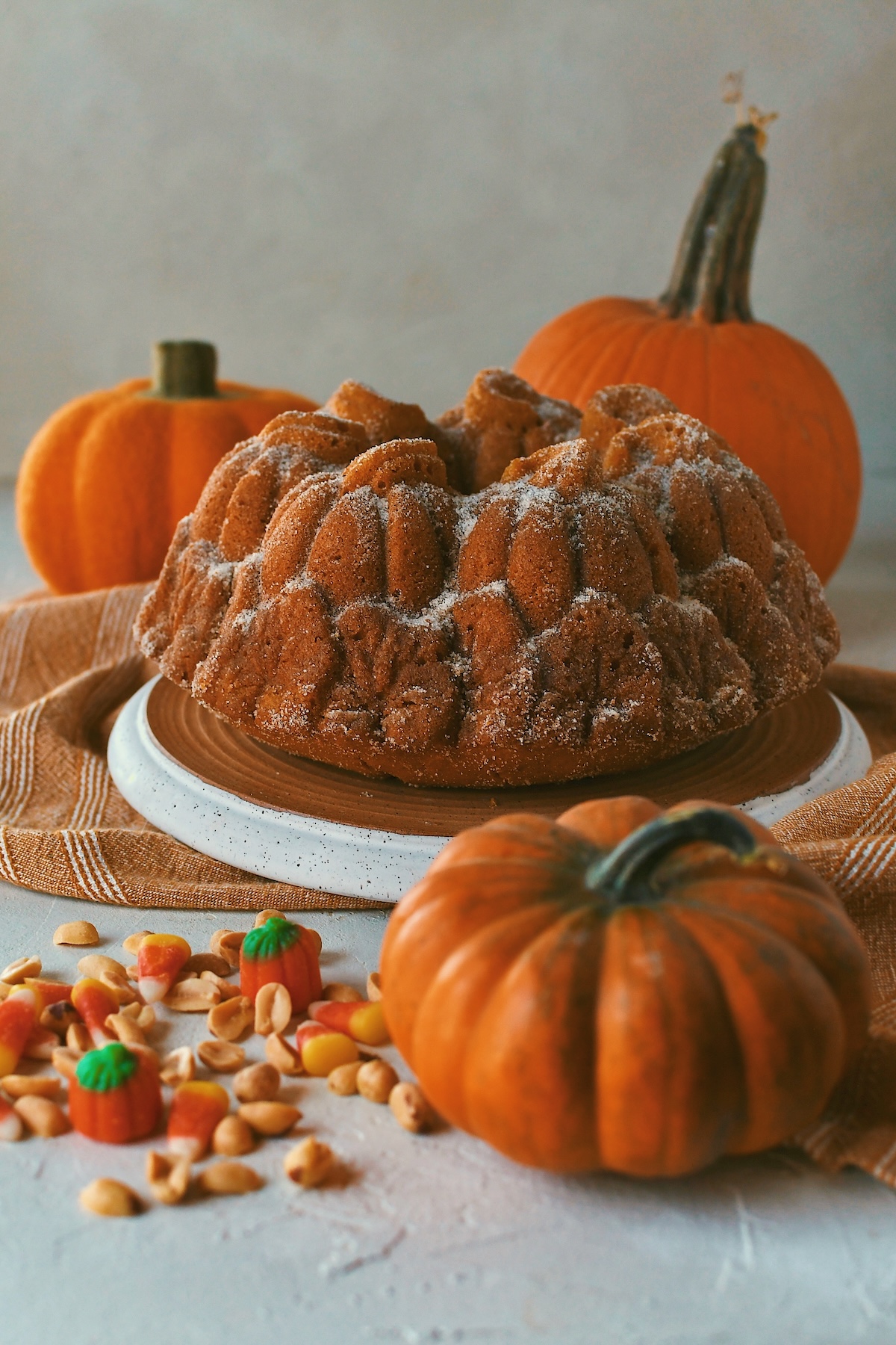 Whole Pumpkin Donut Bundt Cake on a tray surrounded by pumpkins and candy corn and peanuts.