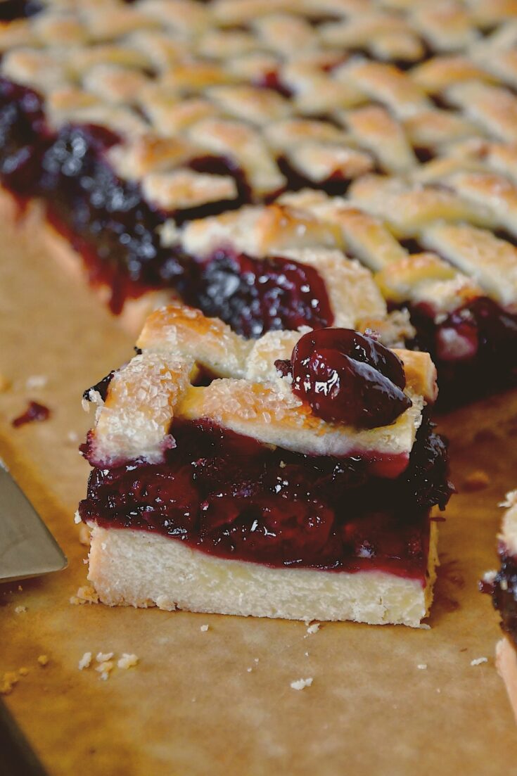 Looking into a cherry pie bar freshly cut on the cutting board.