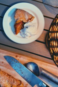 Peach Galette cut in a board and a slice on a plate with a side of ice cream on the back patio on a summer night!